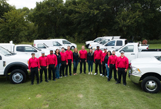 Group photo of Employees in uniform with company trucks