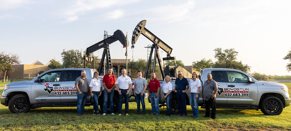 Group photo of Pest Force Employees in uniform with company trucks