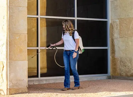 Pest control technician spraying along exterior wall