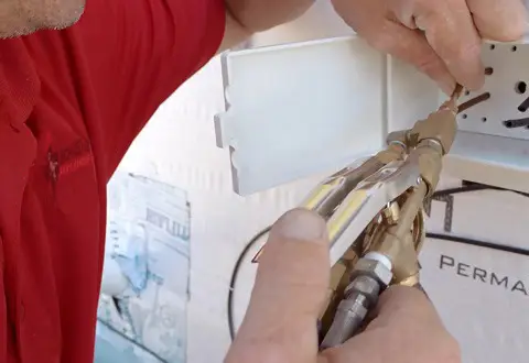 Pest control technician applying treatment inside wall